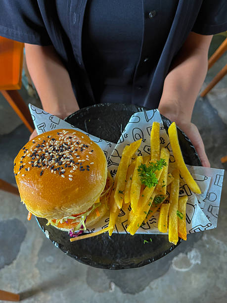 A person is holding a plate with a burger and fries