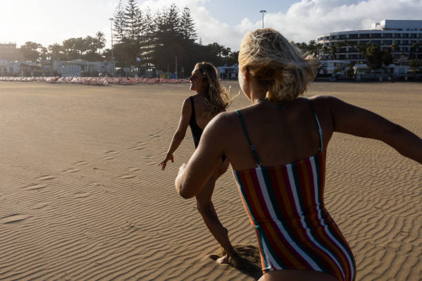 istock Tourists jogging along sandy shoreline during golden sunrise, approaching ocean waters 2194511085