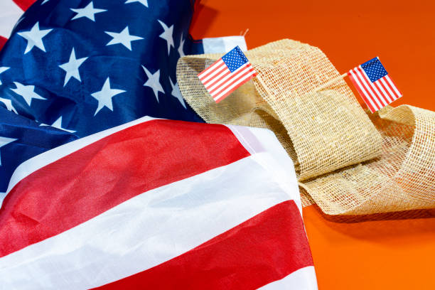 Large American flag with two other small ones on an orange background