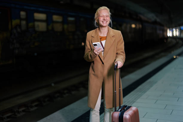istock Businesswoman waiting for the train at night using her smartphone 2194513177