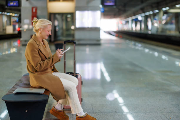istock Businesswoman using smartphone while waiting for train at station 2194513199