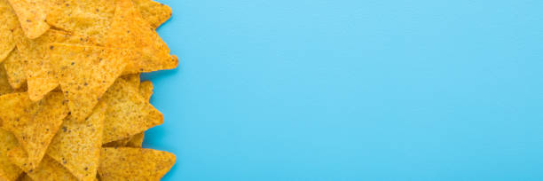 istock Yellow tortilla chips on light blue table background. Pastel color. Wide banner. Closeup. Empty place for text. Top down view. 2194513367