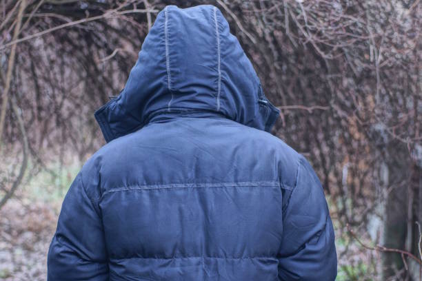 istock one man in a black jacket and hood stands with his back 2194517050