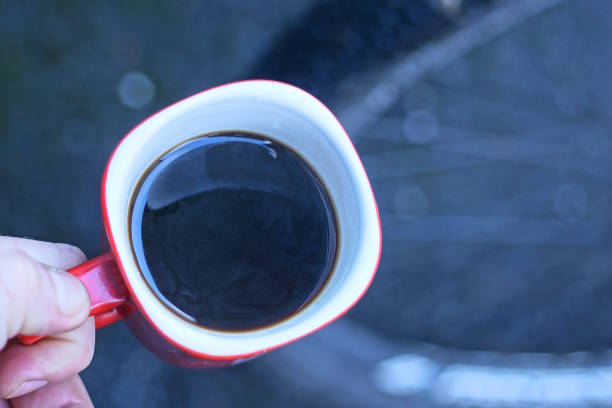 hand holding one ceramic red white cup with black coffee