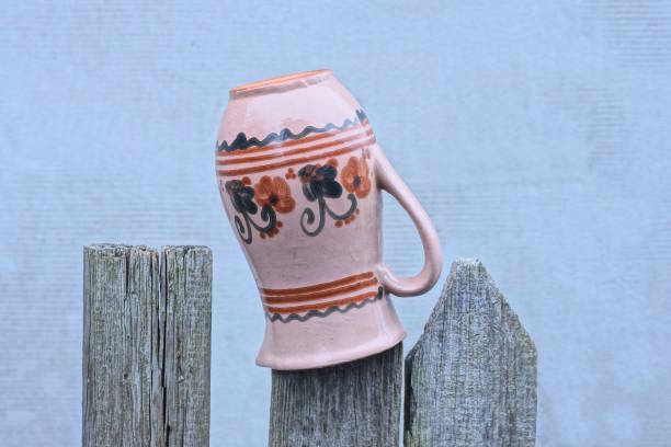 one old brown ceramic big jug hanging on gray wooden board fence on rural street