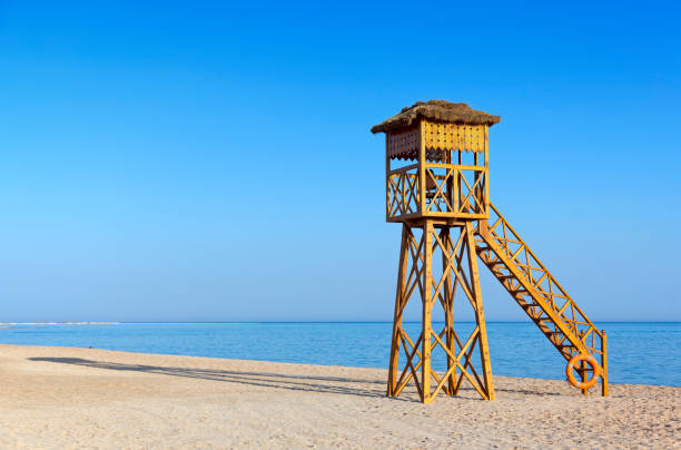 Wooden lifeguard chair on tranquil beach against clear blue sky