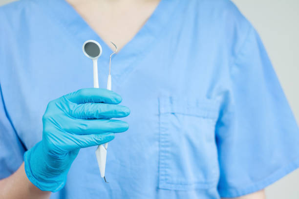 Dentist conducts diagnosis and training using instruments and artificial jaw for practice, close-up.