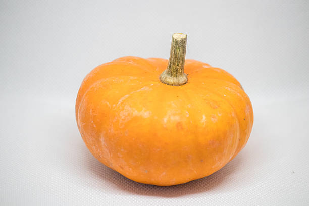Vibrant orange pumpkin resting on a neutral background, perfect for autumn decorations and seasonal cooking inspirations