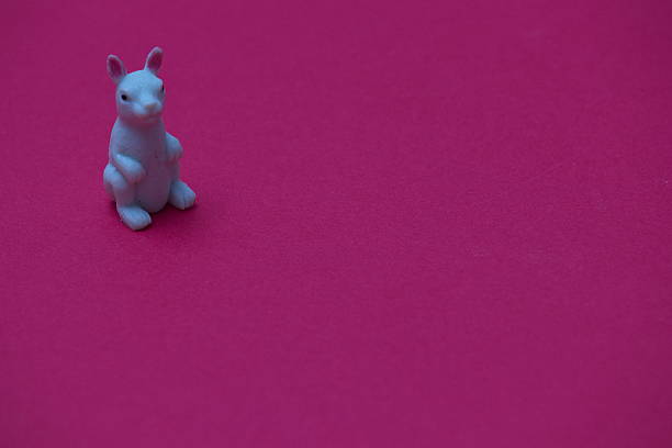 istock Small white rabbit toy standing on a vibrant pink background during daylight 2194522623