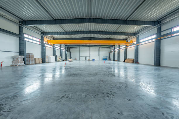 istock Large Industrial Warehouse With Modern Design and Empty Spacious Interior Layout. Yellow Crane In Background 2194525898