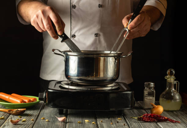 istock An experienced cook expertly maneuvers a knife and fork while stirring the contents of a pot on the stove. Fresh ingredients such as onions and garlic are nearby, adding color to the cooking space 2194525906