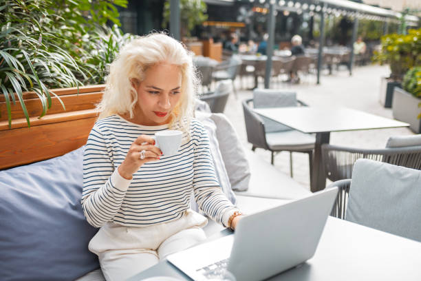 istock Woman Sipping Coffee While Working on Her Laptop Outdoors 2194525949