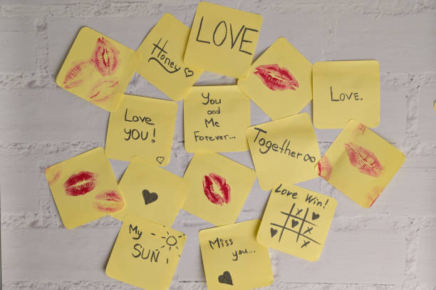 istock Many yellow sticker papers with romantic inscriptions and marks on white brick wall background. Message for Valentine's Day 2194526272