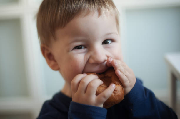 istock Young child enjoys a freshly baked pastry while smiling at the camera in a cozy indoor setting 2194531422