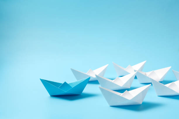 istock Leadership concept with blue paper ship leading among white 2194535571