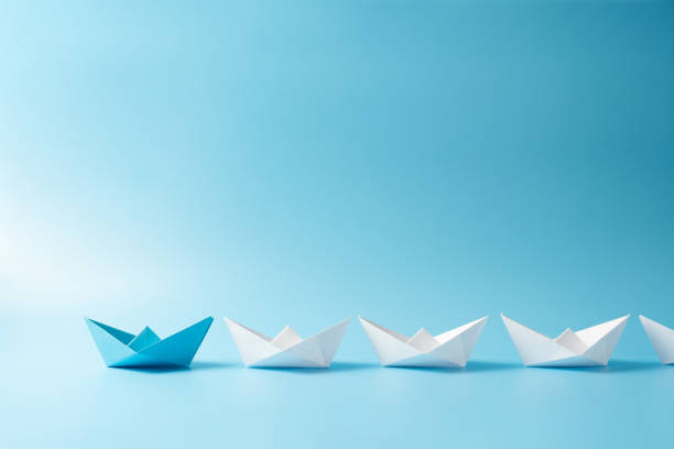 istock Leadership concept with blue paper ship leading among white 2194535682