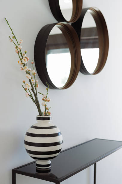 istock Modern interior design showcases a stylish black and white striped vase holding delicate flowers on a sleek console table, with round mirrors adding a touch of elegance to the wall 2194537090