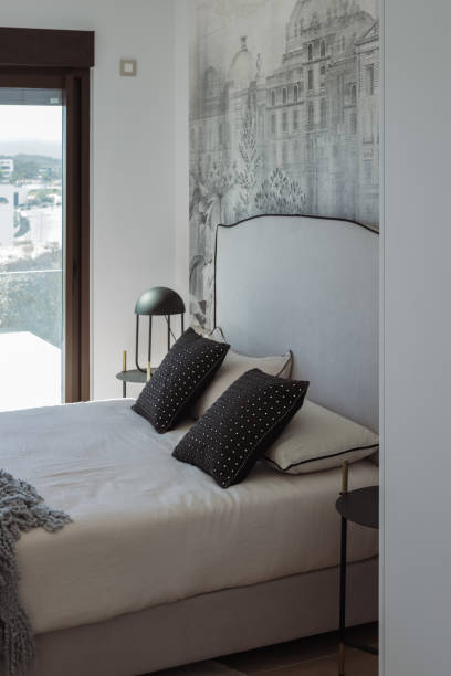 istock Cozy contemporary bedroom highlighting plush bedding, designer lighting, urban wall mural presenting sleek, minimalist sleeping space with sophisticated design elements 2194537103