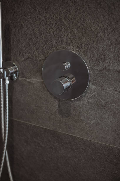 istock Chrome shower faucet featuring polished metallic finish, mounted on dark grey textured tiling, highlighting contemporary bathroom design elements 2194537104