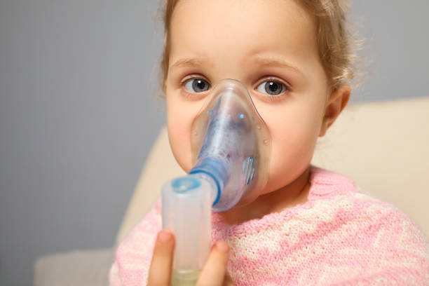istock A young child sits comfortably in a cozy living room, using a nebulizer while wearing a face mask. The soft colors and warm atmosphere create a sense of security during the treatment 2194537842