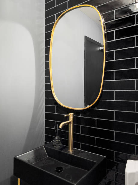 A bathroom with black tiles and gold accents.