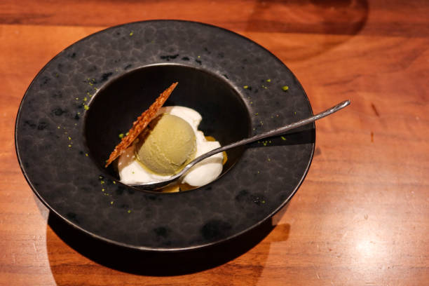 istock Green tea ice cream with a crispy biscuit on the side and cream in a black plate with tea spoon 2194541764