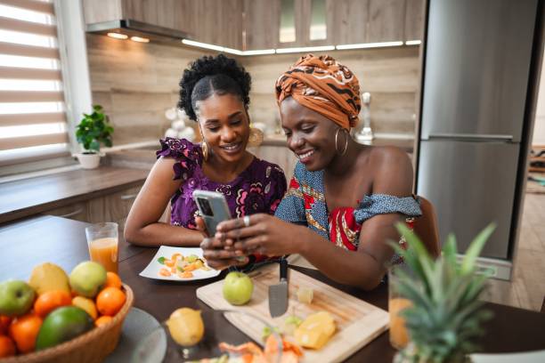 istock Two smiling women looking at smartphone in kitchen 2194541942