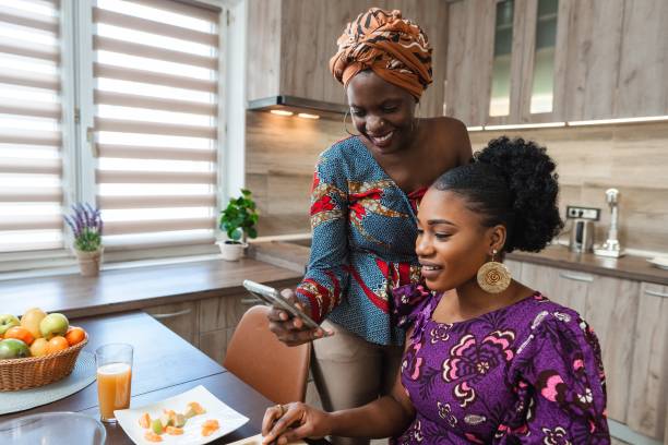 istock Two smiling women sharing a moment and looking at smartphone in kitchen 2194541954