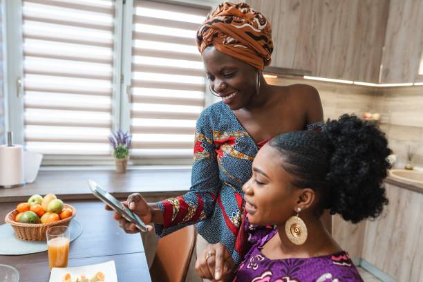 istock Two smiling women sharing a smartphone at home in the kitchen 2194542026