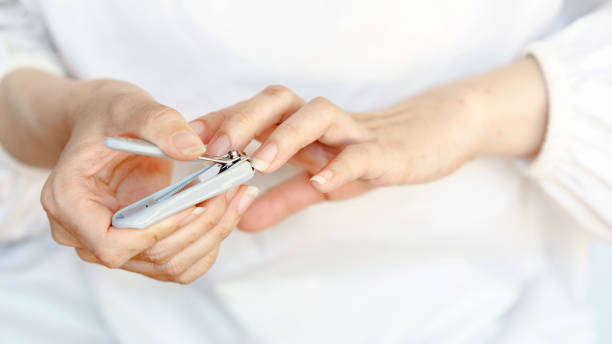 istock Close-up of hands using nail clippers to trim fingernails, emphasizing personal hygiene and grooming on a neutral background. 2194543096