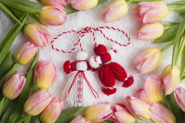 Martenitsa, Martisor, on snow framed with pink tulips