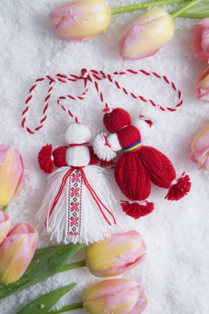 Martenitsa, Martisor, on snow framed with pink tulips