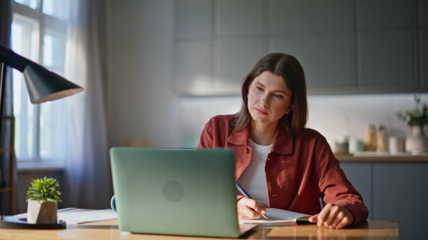 istock Remote worker noting work tasks in copybook listening boss at laptop closeup 2194545439