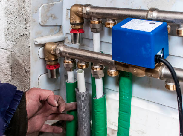 istock Close-up of a plumbing system with green insulation and a blue control box, showing a hand adjusting the pipes. Suitable for heating or water distribution. 2194546724