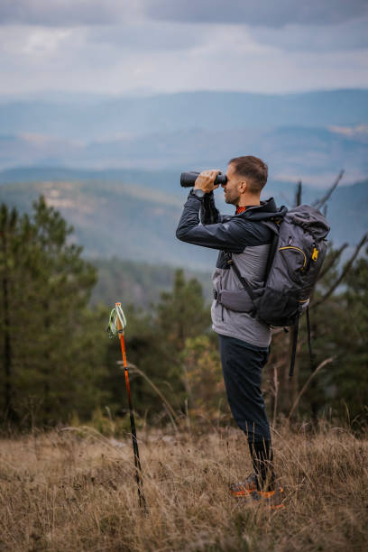istock A hiker uses binoculars to observe distant landscapes while trekking on a mountain trail during an overcast afternoon 2194554287