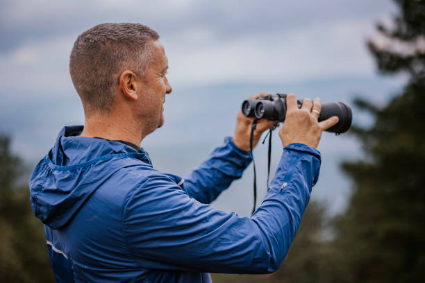istock Person observing nature through binoculars on a cloudy day in a scenic outdoor setting 2194554393