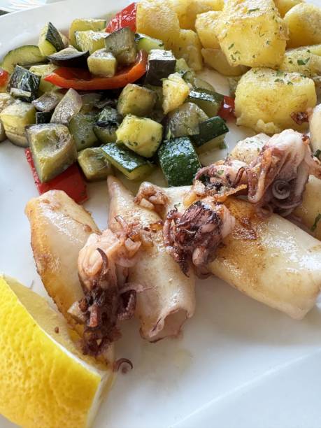 istock Grilled squid with roasted vegetables and potatoes on a white plate with lemon slice 2194563366