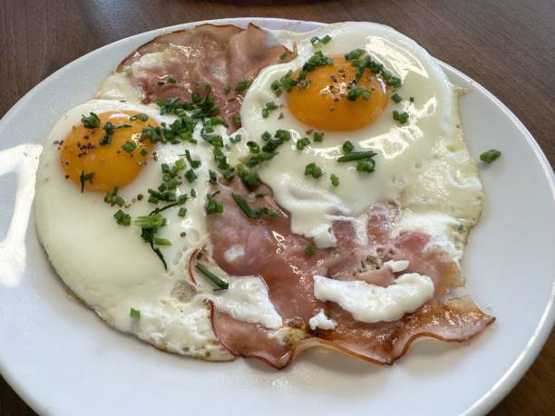 istock Sunny side up eggs with ham and chives on white plate, breakfast 2194563415