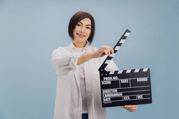 istock Smiling woman using movie clapperboard on blue background 2194563465