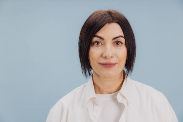istock Confident mature woman smiling on light blue background 2194563599