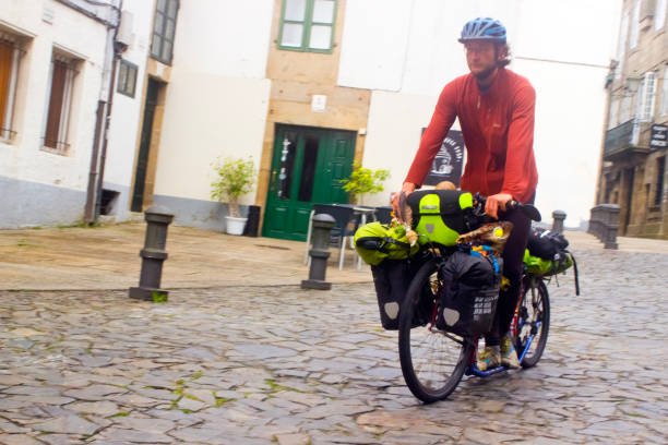 Pilgrim cyclist, young man riding along old town street in Santiago de Compostela, Galicia, Spain. The 'camino de Santiago' is an ancient pilgrimage route which belongs to the UNESCO world heritage.