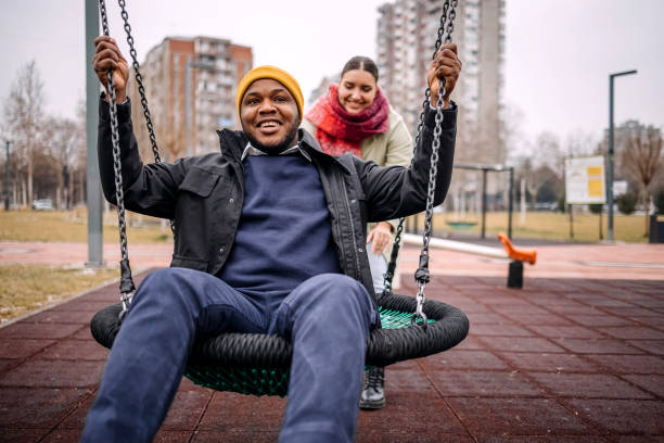istock Young adults having fun in public park swinging each other 2194566981