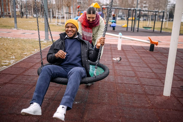 istock Young adults having fun in public park swinging each other 2194566986
