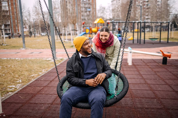 istock Young adults having fun in public park swinging each other 2194566998