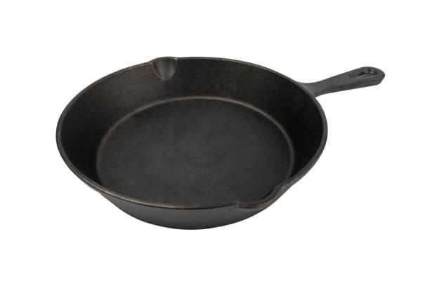 Empty black cast iron cooking pot with wooden spoon and bread on a rustic table
