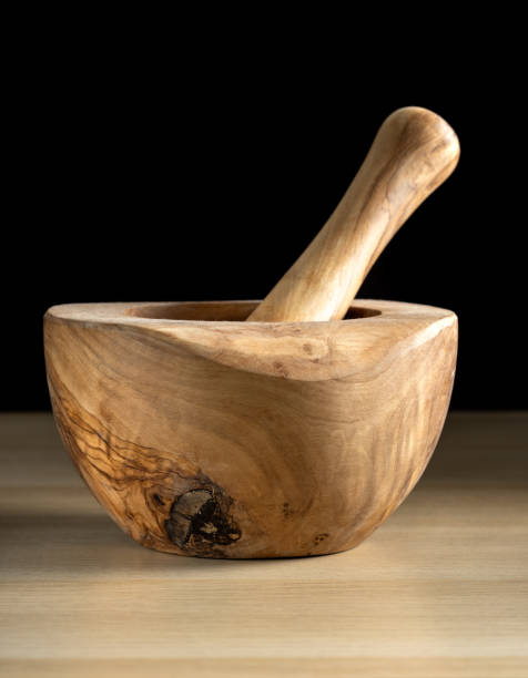 Nice wooden mortar and pestle resting on a wooden table.