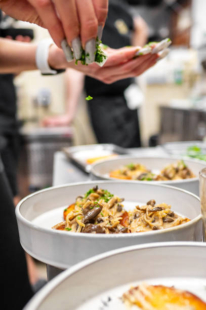 istock A chef sprinkles fresh herbs over elegantly plated gourmet dishes in a bustling kitchen. The vibrant colors and textures highlight the culinary creativity in a professional cooking environment. 2194572490