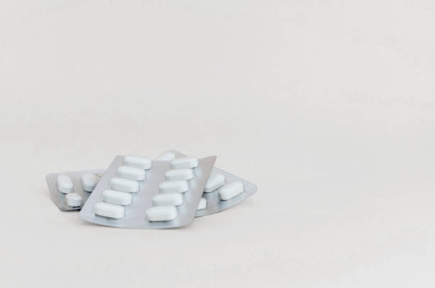 Three blister packs of tablets on light pastel background, close-up. Pharmaceutical industry concept, medicine, treatment. banner, space for text