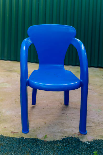 istock Bright blue plastic chair placed on a concrete surface in an outdoor setting surrounded by a green backdrop 2194575207