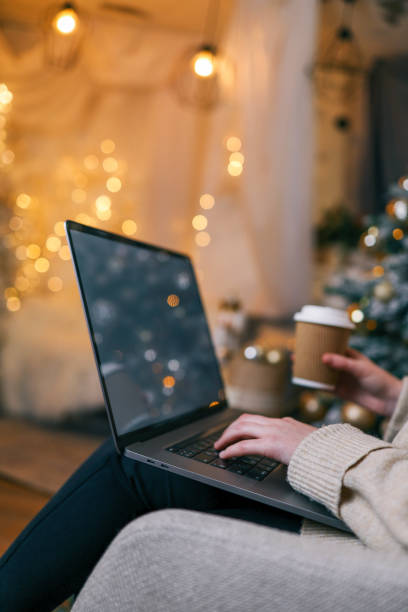 istock Hands typing on a laptop with a beautifully glowing Christmas tree in the background, creating a cozy and festive atmosphere indoors 2194576125